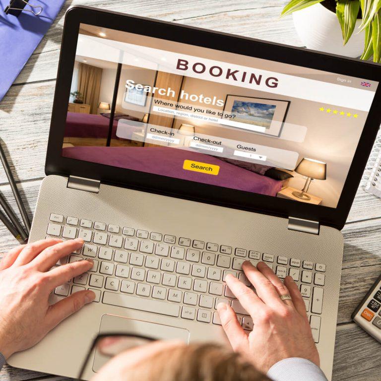 Laptop with hotel bookings on screen - hands on keyboard looking for a good hotel deal.