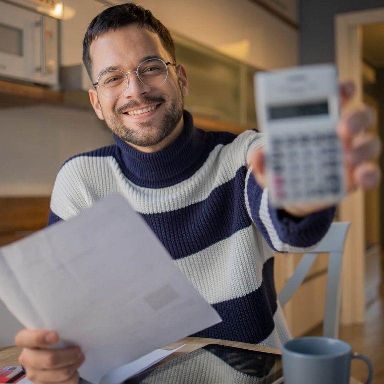 Smiling man reviewing his debt proudly holds calculator up to camera.