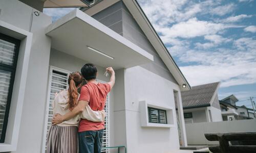 Happy couple standing outside of the new home they purchased with an adjustable rate mortgage.