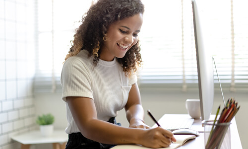 Woman seated at desk smiling, going over her finances.