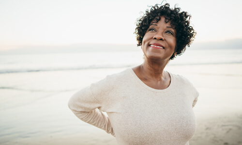 Smiling woman outdoors on beach contemplating retirement