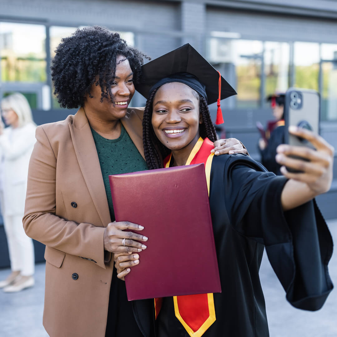 Mother taking selfie with college graduate daughter.