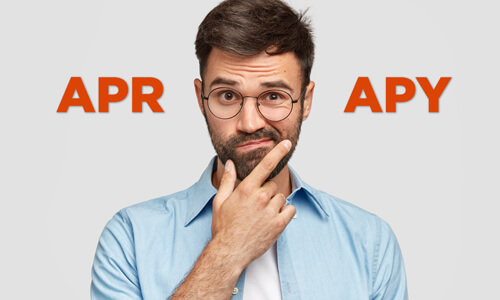 Man looking confused with the word APR over one shoulder and APY over the other.