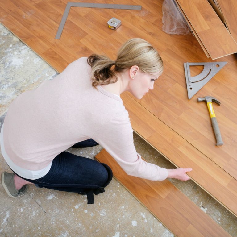 Woman installing floor into her home.