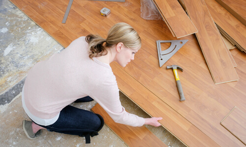 Home improvement DIY: Woman installing floor into her home.