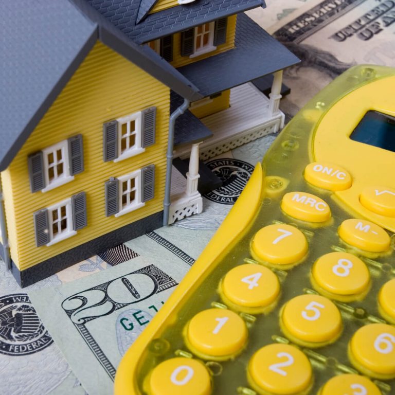 Yellow model house and yellow calculator on dollars bills.