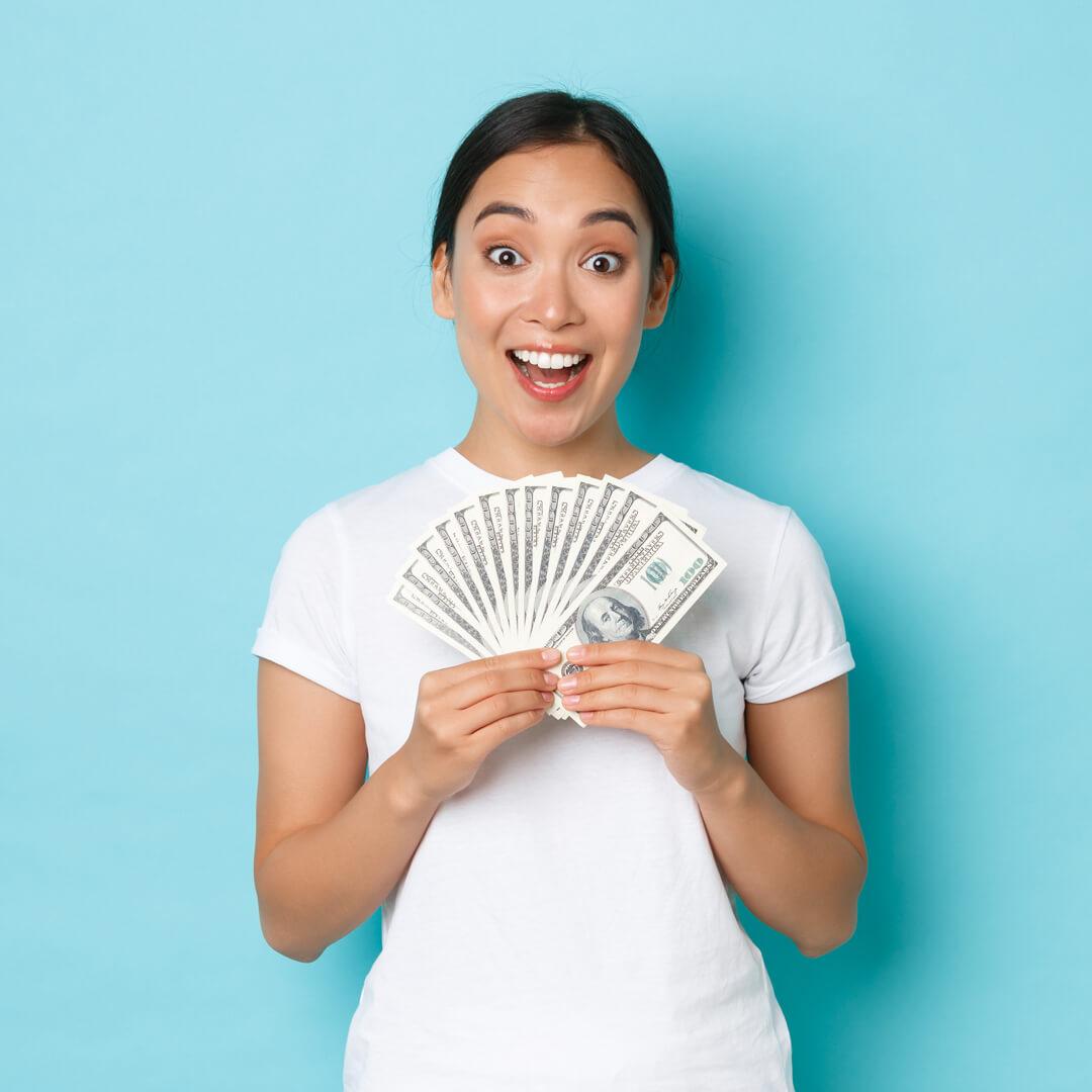 Happy woman holding hundred dollar bills, because of early direct deposit.