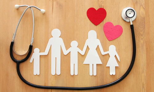 Paper cutout of family with hearts, a real stethoscope surrounding the cutouts.