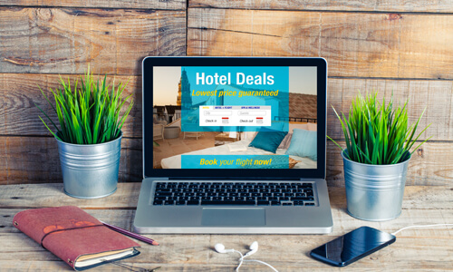 Laptop on desk with "Hotel Deals" displayed on screen.