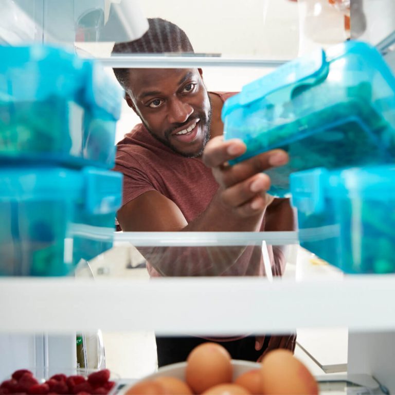 Man getting leftovers out of his refrigerator.