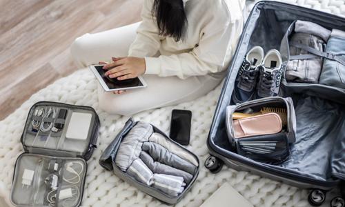 Woman with suitcase packing her valuables before a trip