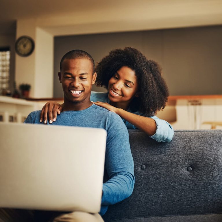 Man and woman on couch opening up a joint checking account.