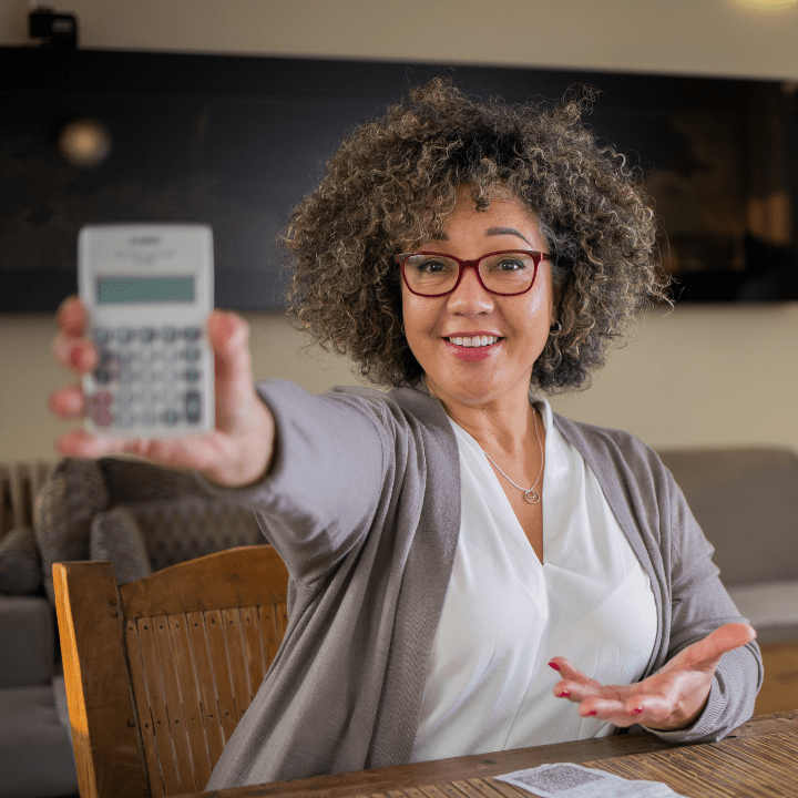 Woman with curly hair shows off her calculator while doing her taxes.
