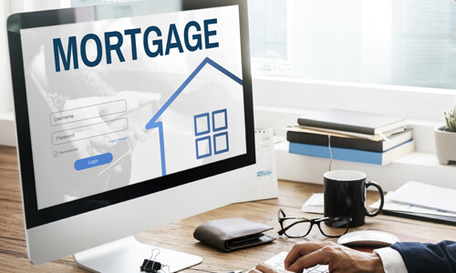 Man looking at computer screen with "Mortgage" displayed on it.