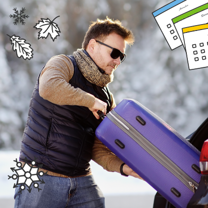 Man placing purple suitcase in the trunk of his car with a snowy background.