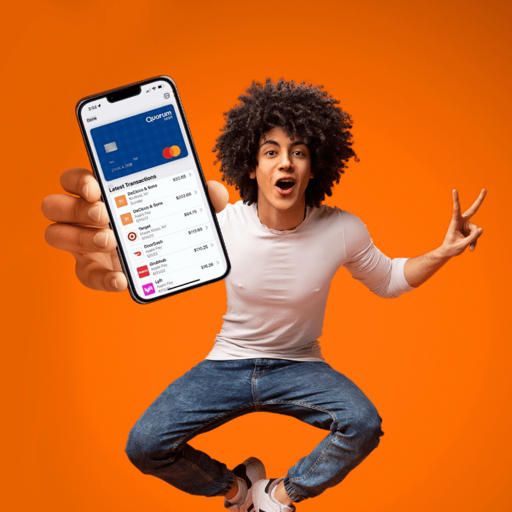 A young man jumps with joy as he shows his phone that displays QClassic Checking: Quorum’s FREE online checking account with no minimum balance requirements.