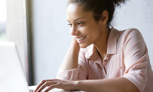 Woman smiling at desk looking at her computer screen.
