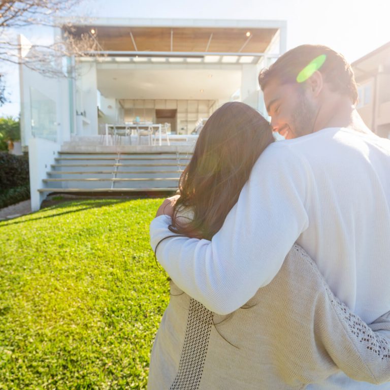 Couple who are new vacation rental owners look at their purchase and embrace.