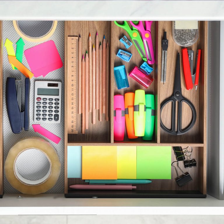 Office and school supplies organized in a desk drawer.