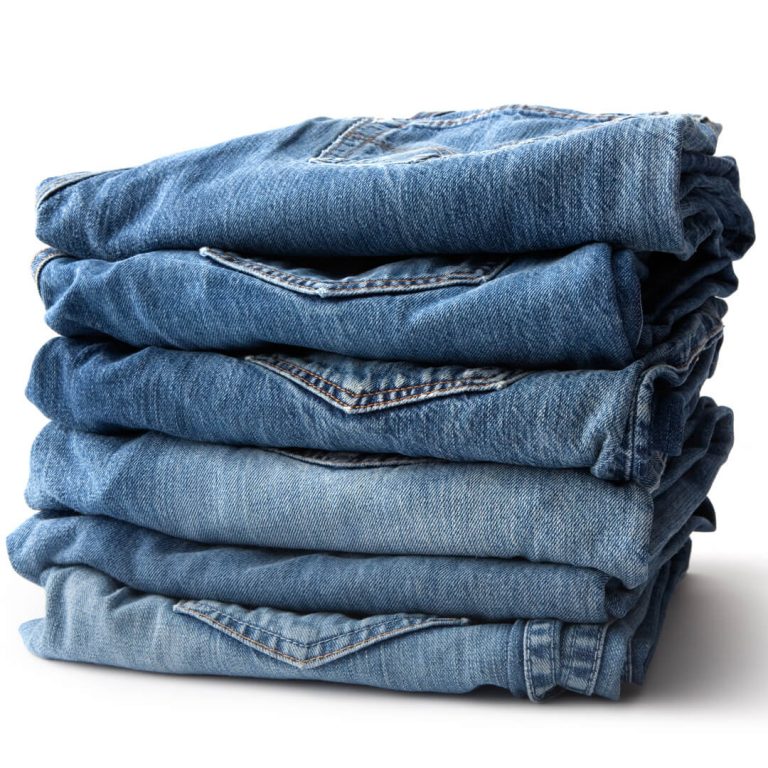 Neatly folded jeans stacked up against a white background.