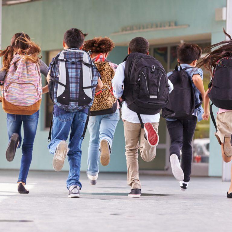 Group of children running towards school.