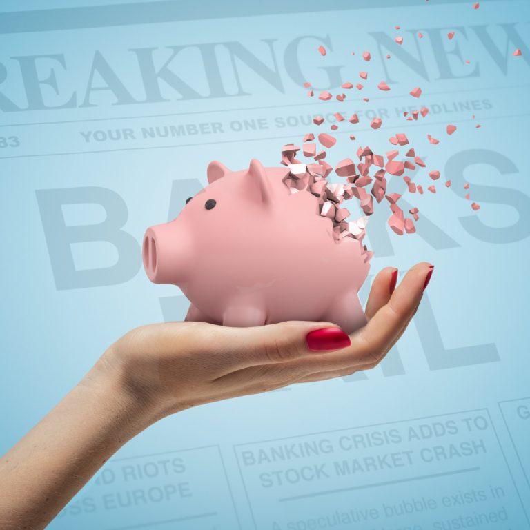 Disintegrating piggy bank over a newspaper that says "Banks Fail" Breaking News.