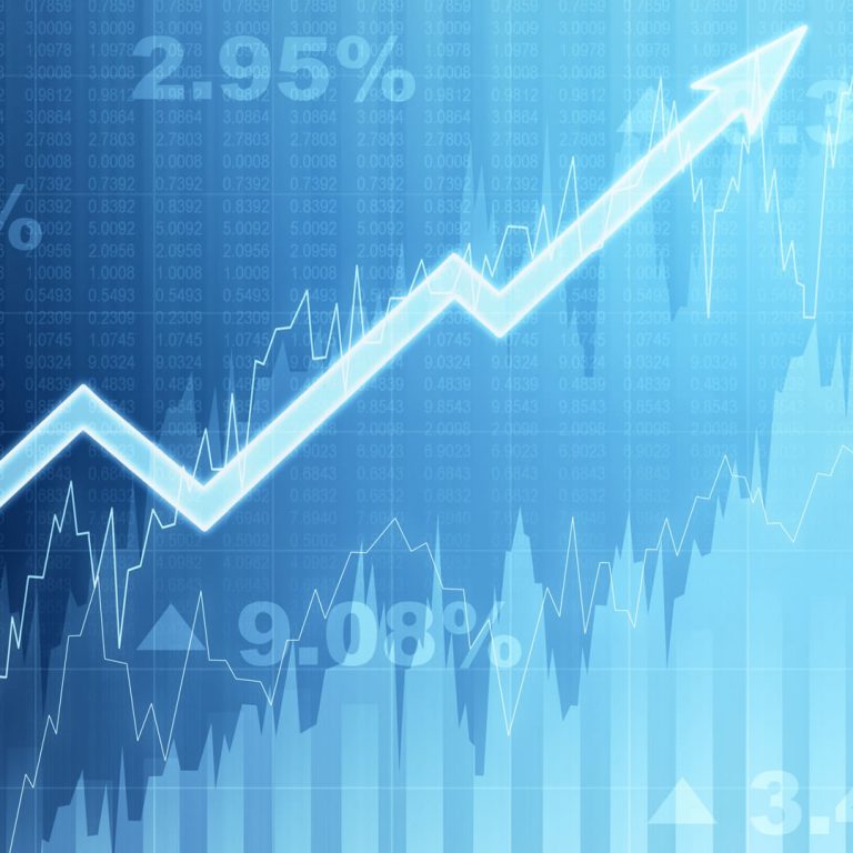 Investing concept: arrow trending up on blue stock exchange screen.