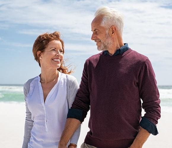 A couple walks on the beach secure knowing their Quorum checking and savings accounts are secure and accessible.