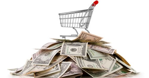 Grocery shopping cart on top of a pile of saved money.
