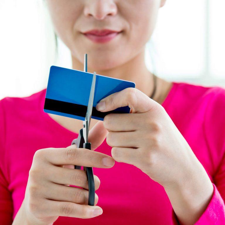 Woman cutting up a credit card, going credit card free.
