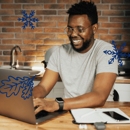 A smiling young adult man on his laptop at home.