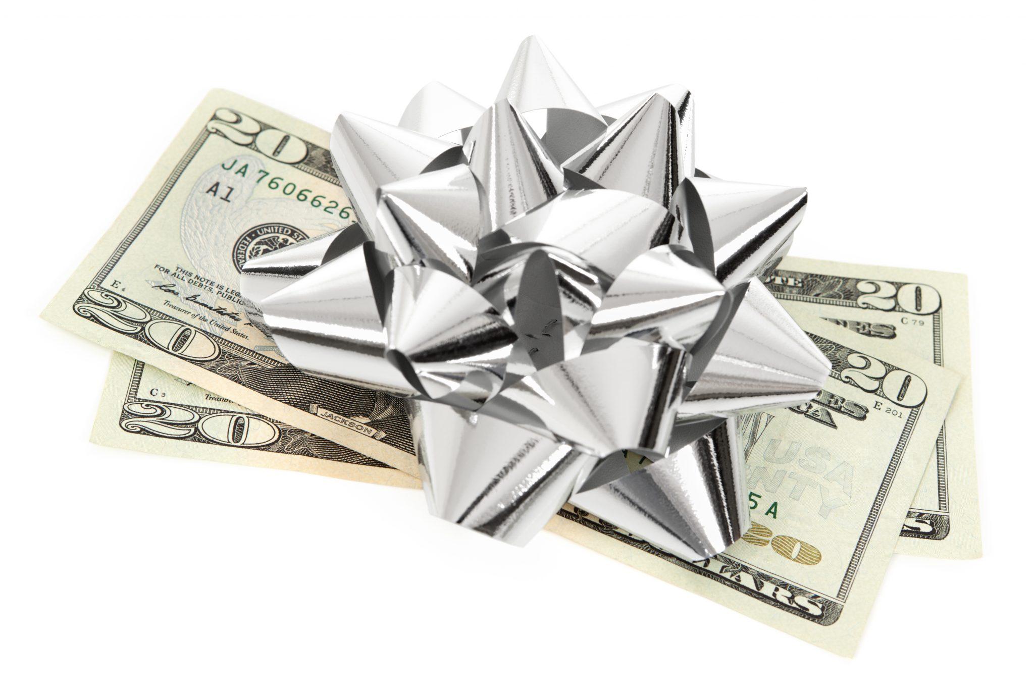 A stack of twenty dollar bills with a holiday silver bow on top.