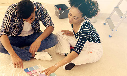 Couple sitting on floor looking at paint samples, ready to do a home improvement project.
