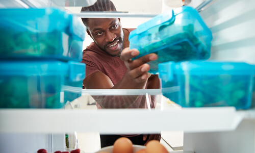 Man getting leftovers out of his refrigerator.
