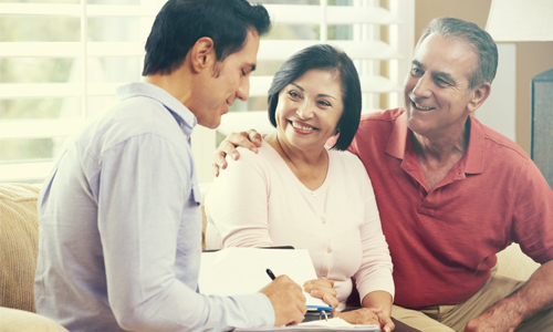 Smiling couple sits with a financial advisor discussing their retirement.