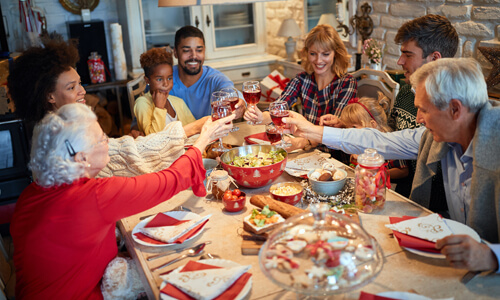Family gathered around holiday table, smiling and enjoying meal.