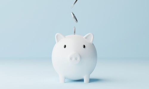 Coins falling from above into a white piggy bank (pay yourself first concept)