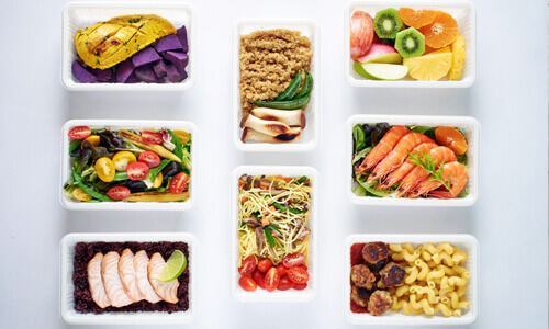Portioned-out meals against a white background, illustrating meal planning and prepping.
