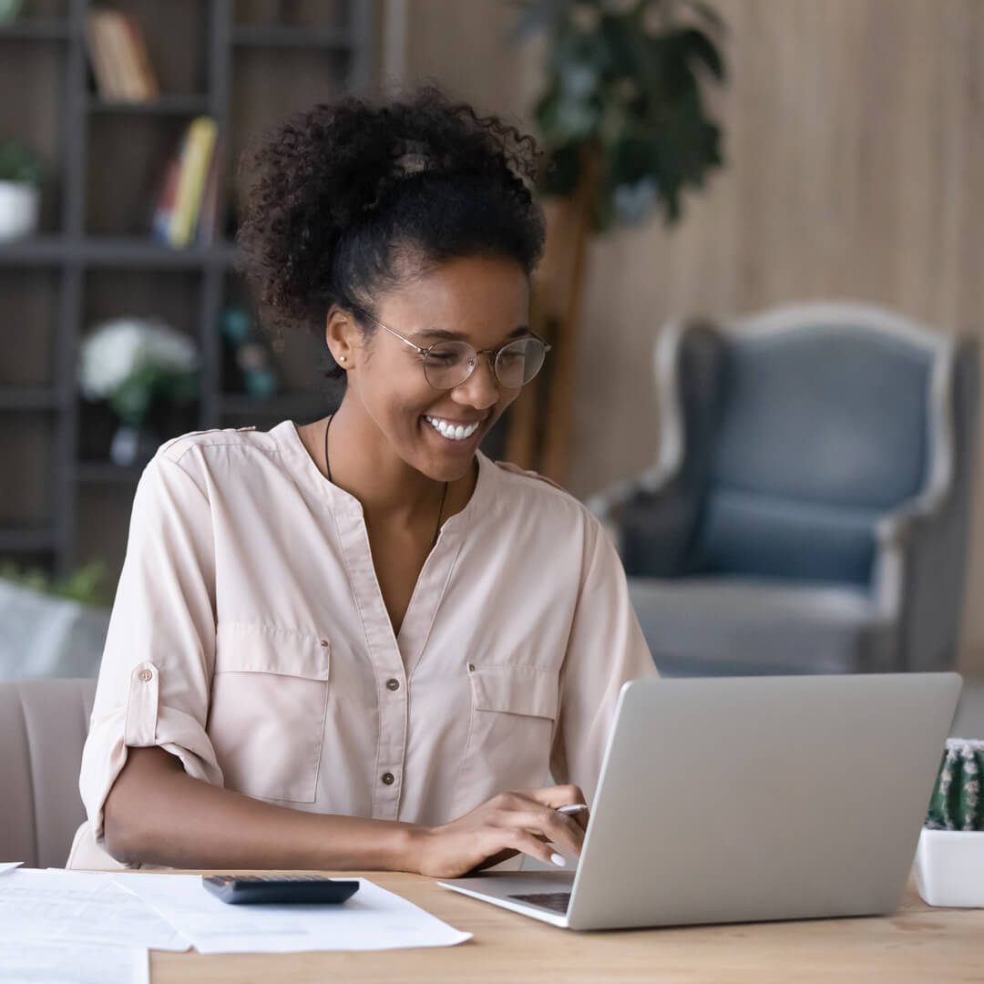 Smiling woman on laptop, paying bills in online banking.