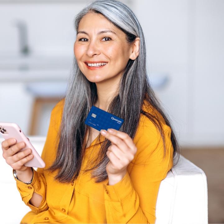 Woman holding a debit card and mobile phone.