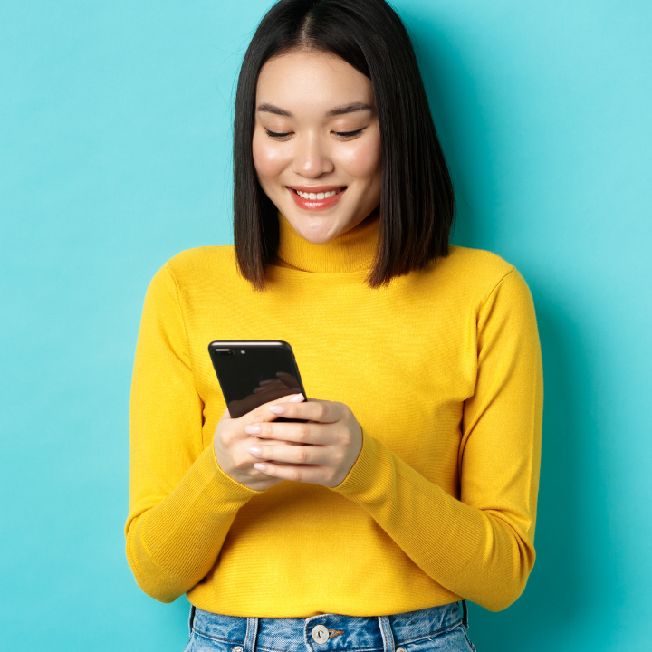 A woman eagerly checks her cell phone for her HighQ savings balance.