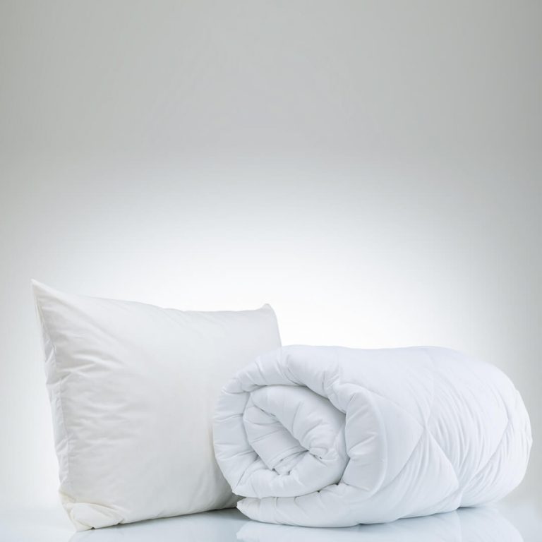 White pillow and rolled up duvet on white background - items that are heavily discounted in January during the White Sale.
