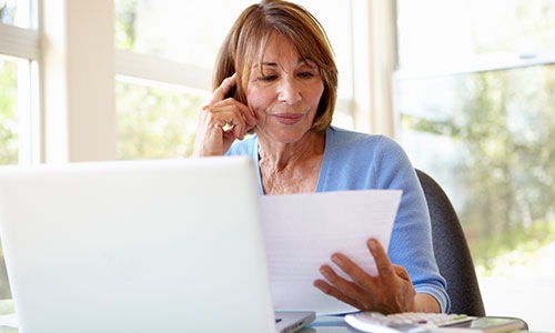 Woman reviewing her finances, sitting in front of her computer.