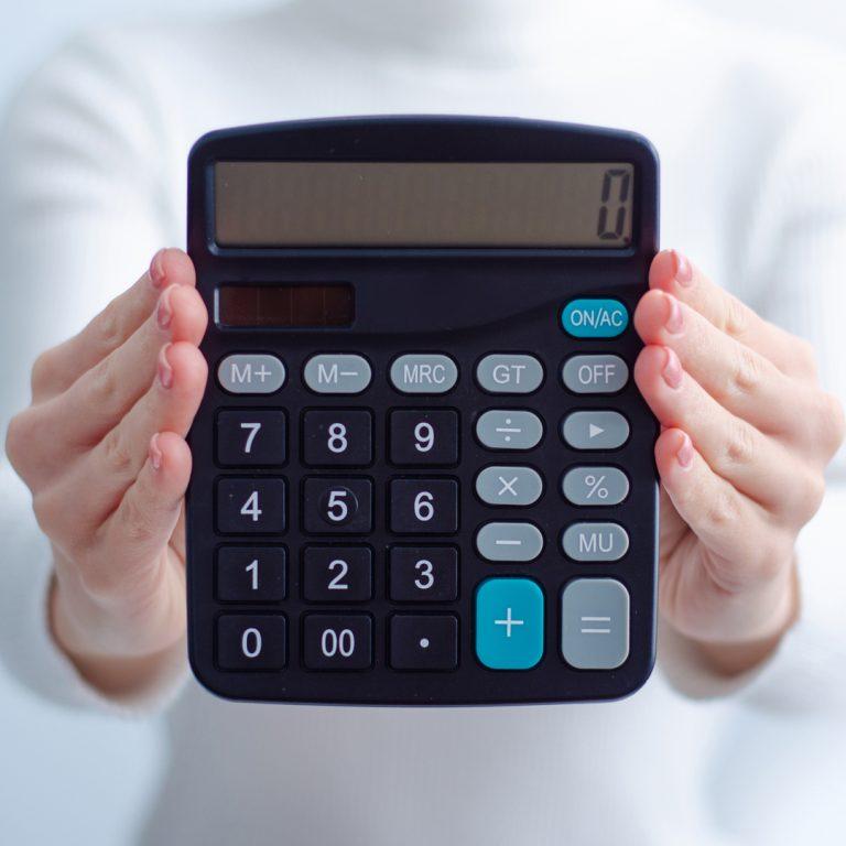 Closeup of hands holding a calculator with "0" in it, illustrating concept of a zero-based budget.